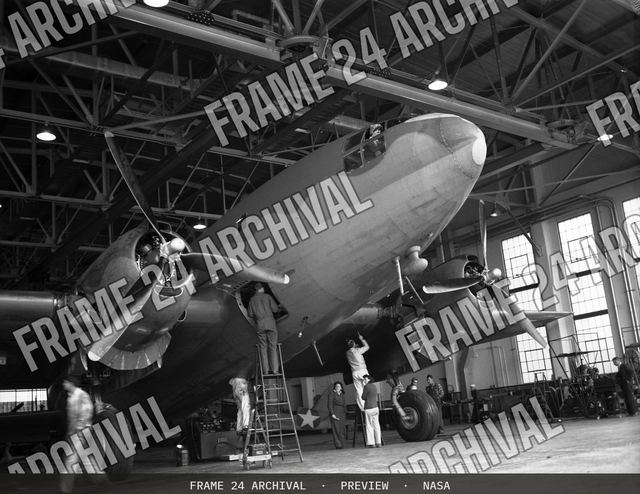 Ames mechanics working on C-46 airplane in front of hangar, vintage black and white photograph