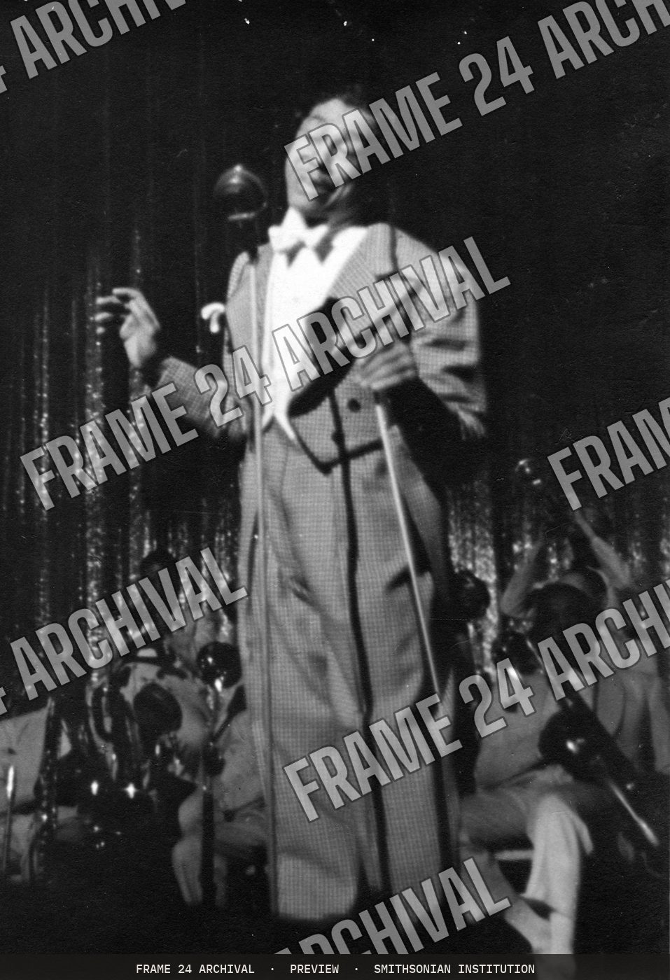 Print of Cab Calloway in checked suit standing in front of microphone (1930), restored vintage black and white photograph