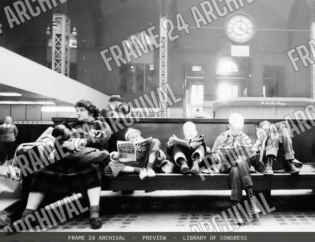 Woman and children seated on bench of train station concourse in Pennsylvania Station, vintage black and white photograph